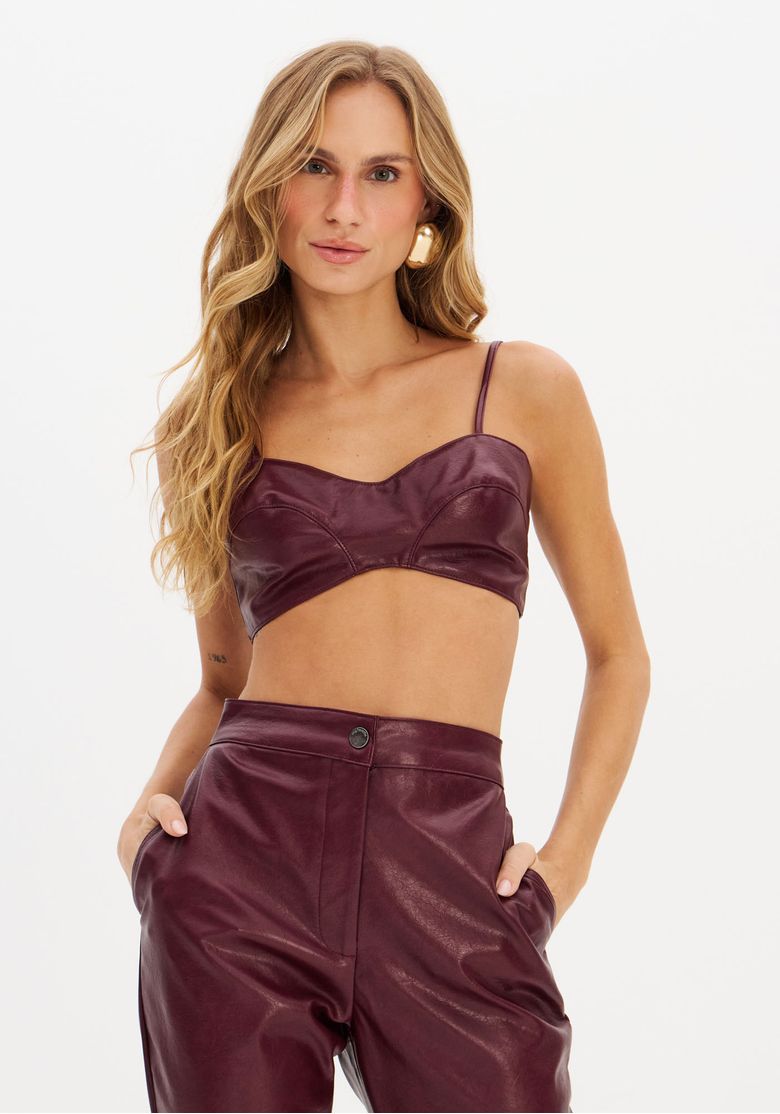 Modelo vestindo top justo em PU bordô com alças finas e calça combinando, vista frontal.