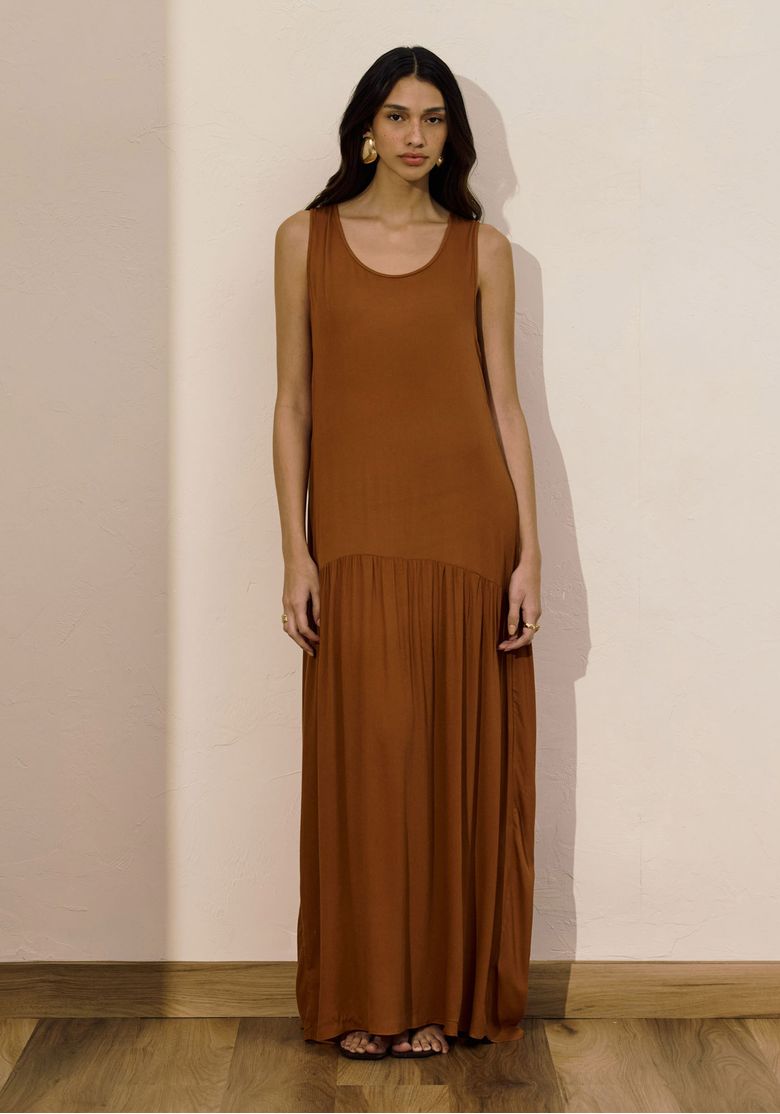 Modelo vestindo vestido super midi marrom com decote U em ambiente interno.