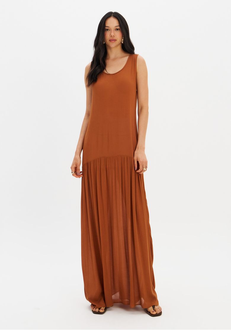 Modelo em fundo branco usando vestido super midi marrom com barra franzida.