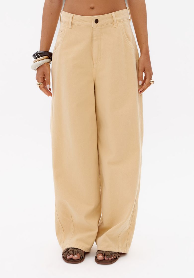 Close frontal da calça sarja super baggy amarelo claro feminina com cintura média, botão frontal e pernas amplas