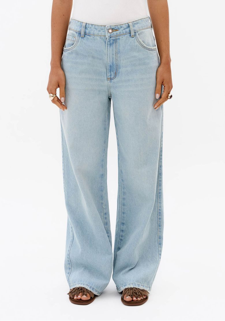 Detalhe frontal de calça jeans feminina azul clara full length com cintura média, bolsos frontais e fechamento por botão e zíper