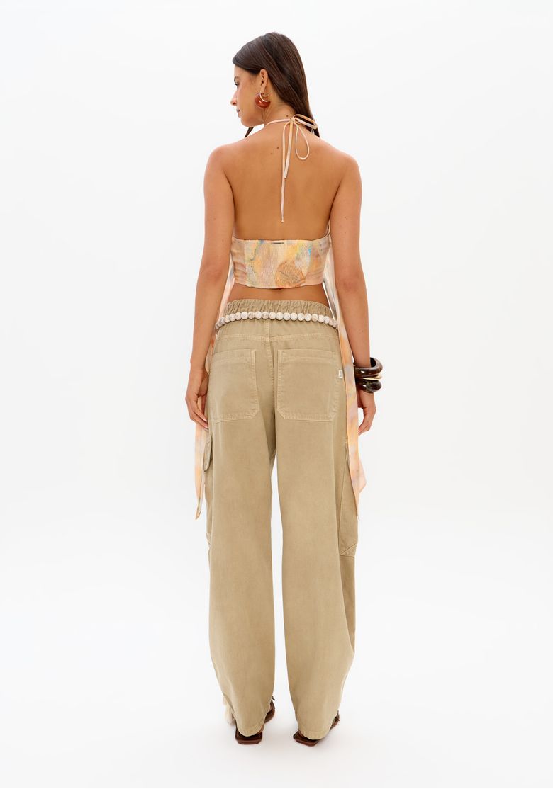 Vista traseira da blusa estampada cropped com costas abertas e amarração, combinada com calça bege feminina