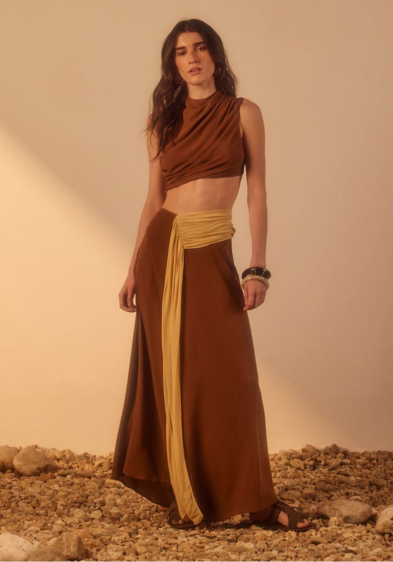 Vestido super midi assimétrico feminino bege e marrom com gola alta drapeada, recorte vazado na cintura e barra fluida em look de festa