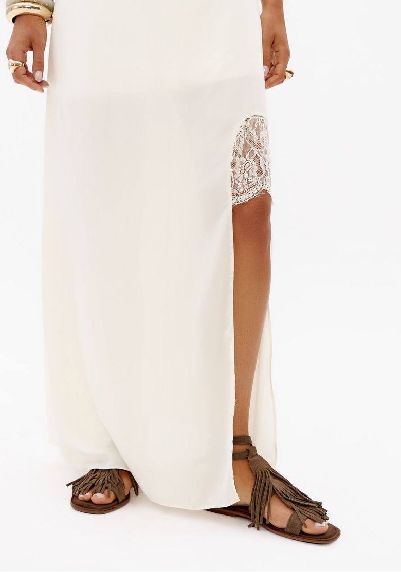 Close da fenda lateral do vestido super midi off white com aplicação de renda e caimento fluido