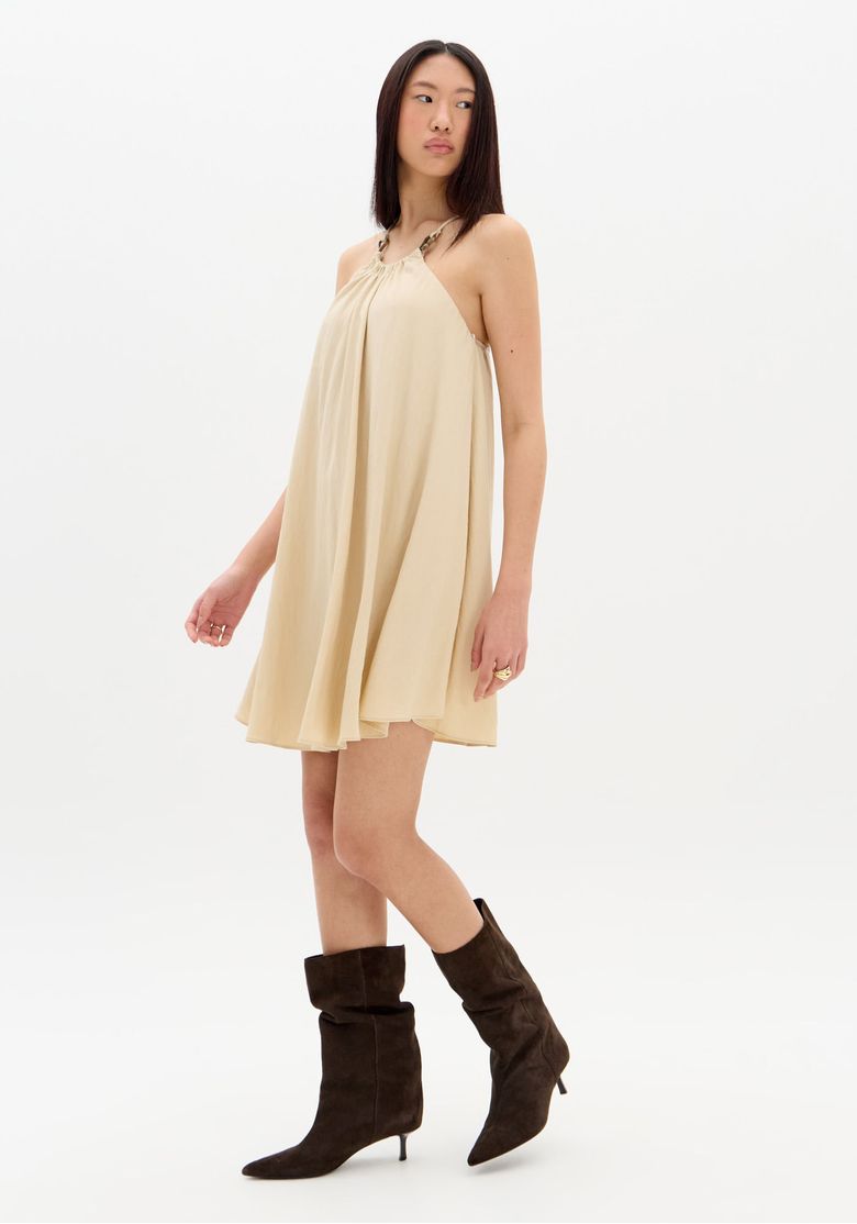 Vista-lateral-do-vestido-gode-bege-em-movimento-destacando-a-silhueta-fluida-e-styling-com-botas-cano-medio---look-casual-urbano