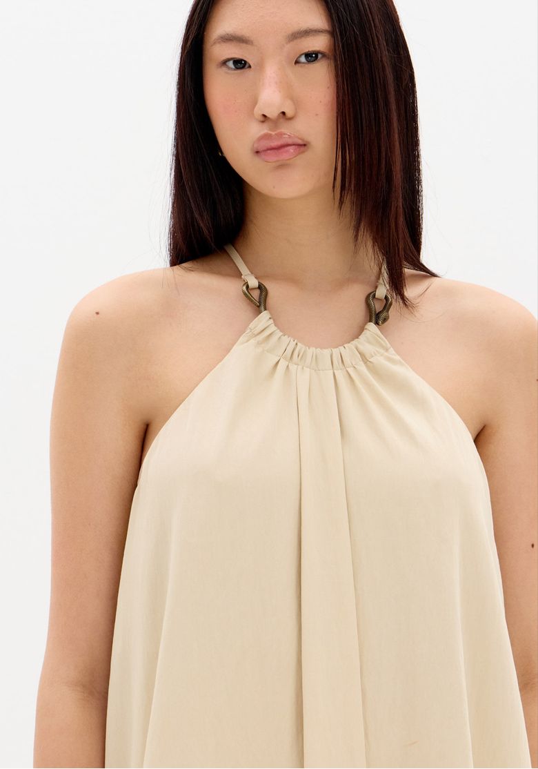 Close-do-decote-halter-do-vestido-bege-com-franzido-central-e-aviamento-em-formato-de-cobra-nas-alcas---detalhe-vestido-halter-bege
