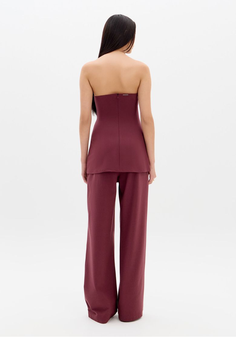 Editorial-com-modelo-usando-macacao-vinho-sem-alcas-e-pantalona-de-perna-ampla-em-cenario-com-painel-de-madeira---look-sofisticado
