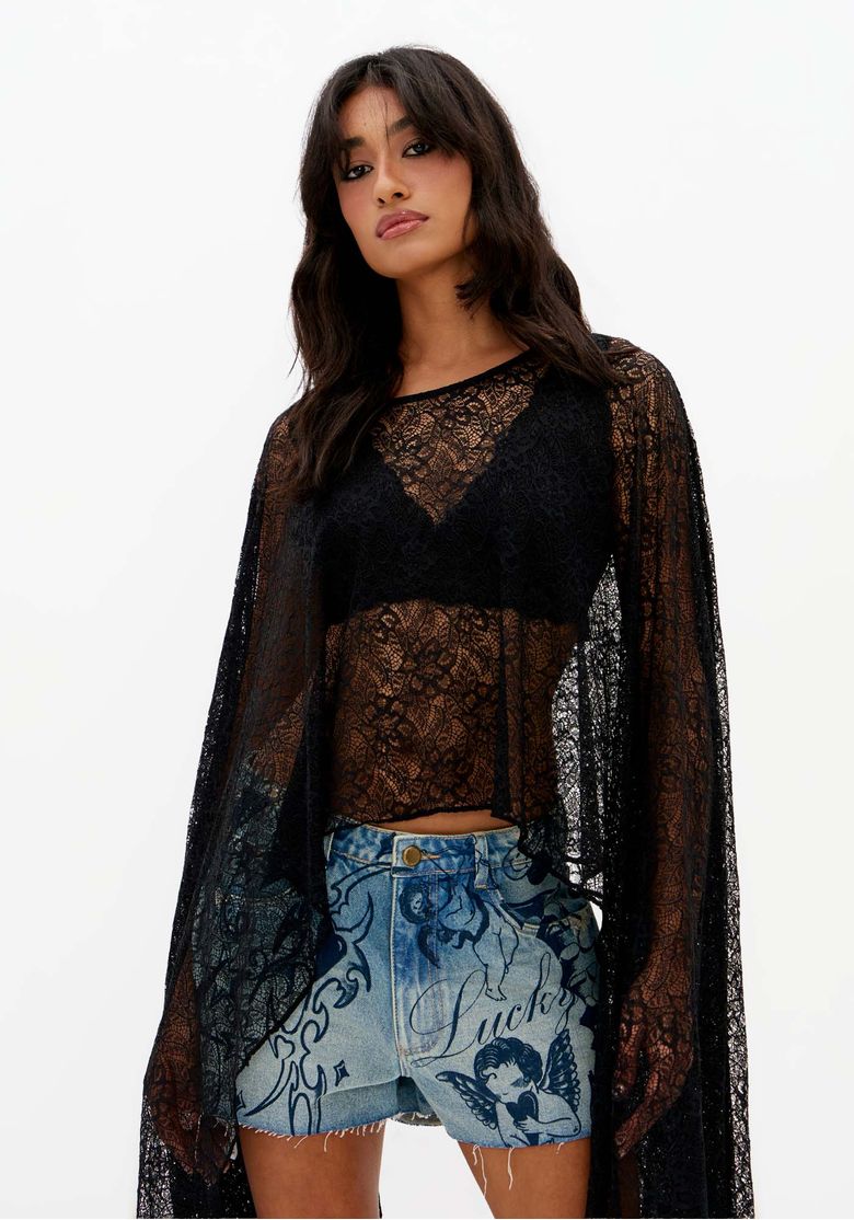 Close-frontal-de-blusa-capa-de-renda-preta-feminina-com-transparencia-gola-redonda-e-caimento-fluido-sobre-short-jeans-claro-estampado