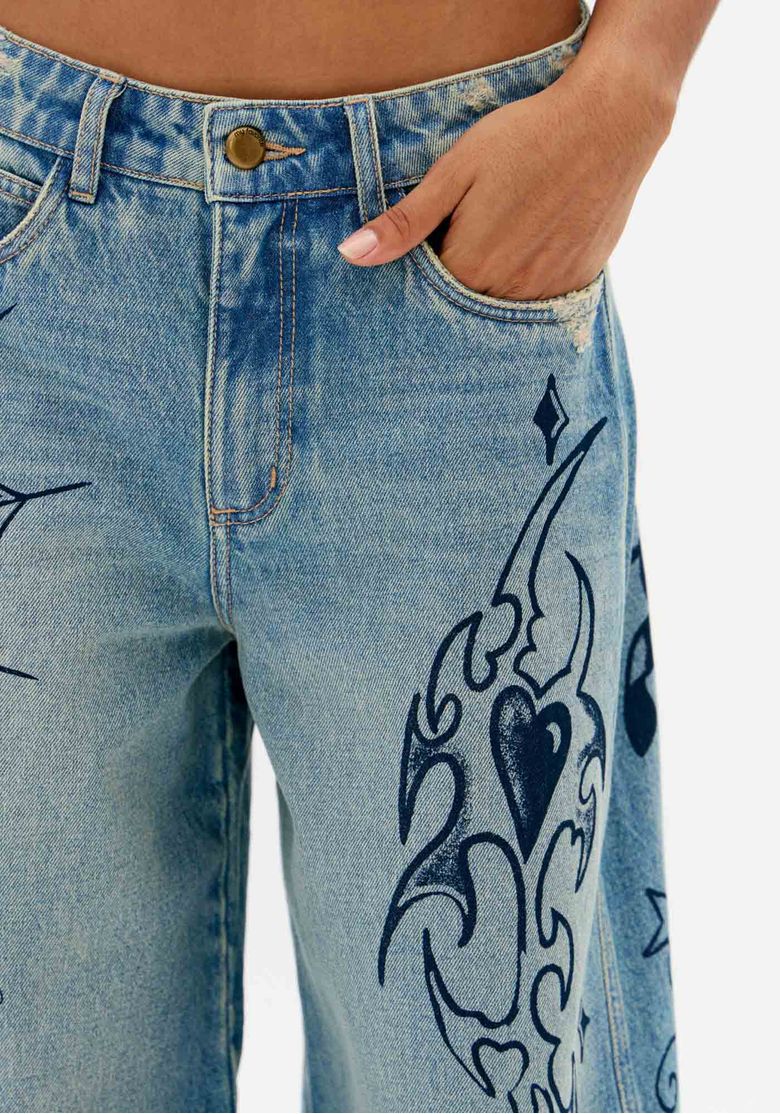 Close-da-cintura-media-da-calca-jeans-azul-com-botao-ziper-bolso-funcional-e-estampa-tattoo-lateral