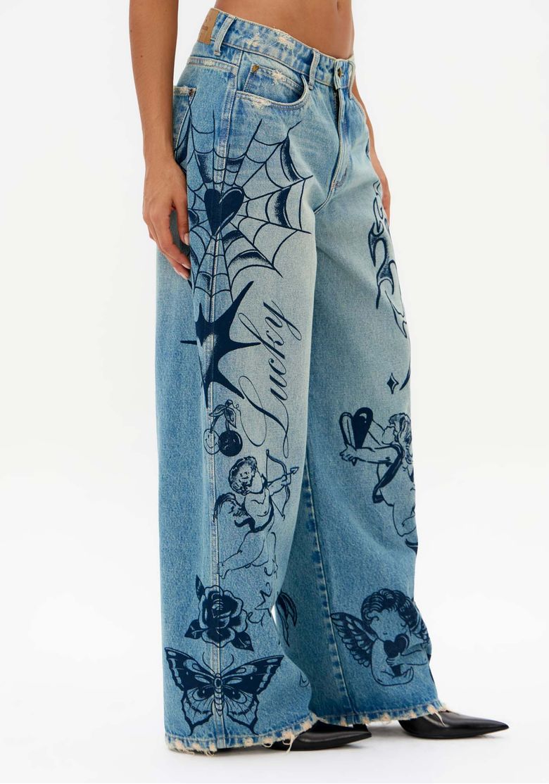 Vista-lateral-da-calca-jeans-wide-leg-azul-com-desenhos-de-teia-coracao-anjos-e-barra-desfiada
