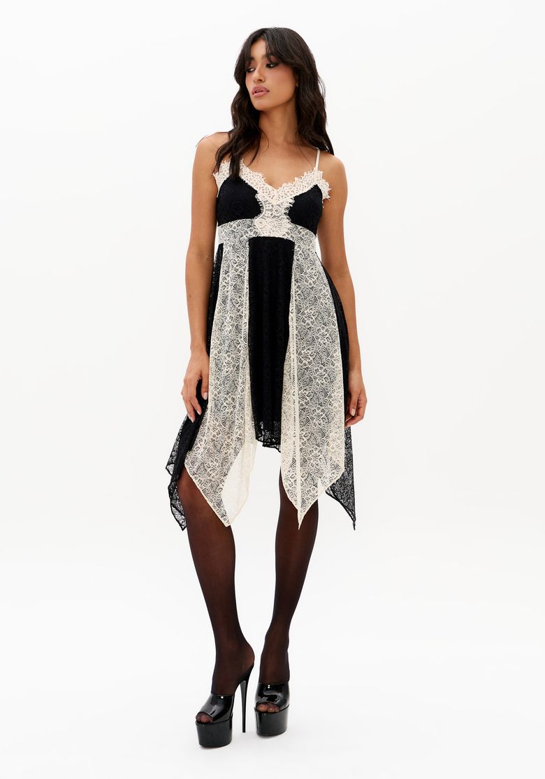 Vestido-curto-assimetrico-preto-com-renda-contrastante-off-white-e-alcas-finas-regulaveis-foto-frontal-com-modelo-usando-meia-calca-e-salto-plataforma