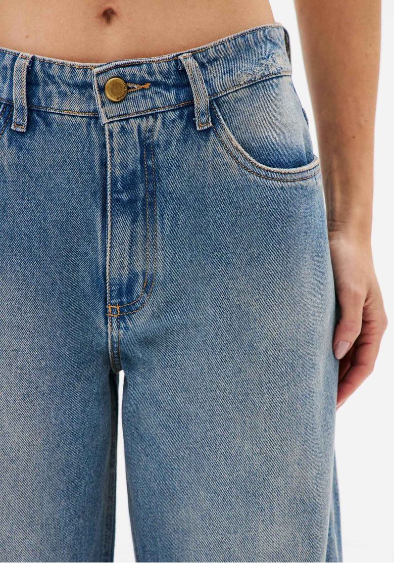 Detalhe da cintura da calça jeans azul x-boyfriend com botão, zíper, passantes e bolso frontal funcional