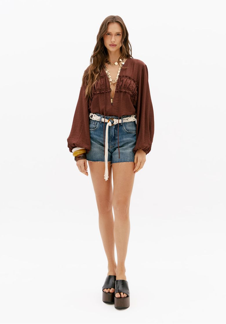 Modelo usando short jeans azul comfort com cinto de cordão e blusa marrom de manga longa em look casual feminino
