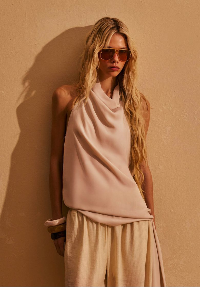 Modelo-usando-blusa-frente-unica-assimetrica-off-white-com-decote-drapeado-e-amarracao-lateral-em-look-elegante-de-verao