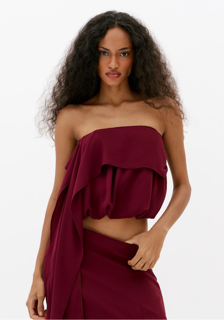 Blusa-cropped-bordo-sem-manga-com-decote-ombro-a-ombro-e-sobreposicao-assimetrica-frontal-em-look-de-festa-feminino