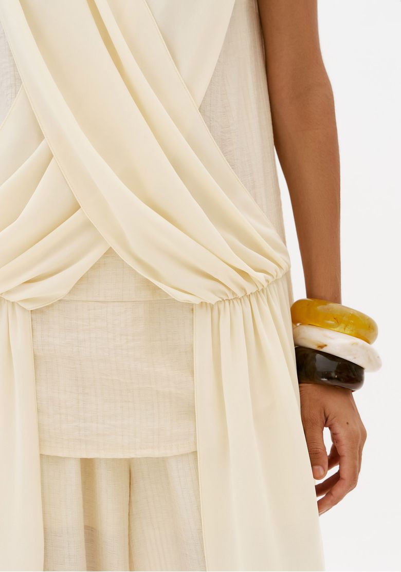 Detalhe-da-blusa-assimetrica-off-white-com-faixa-sobreposta-drapeado-frontal-e-barra-assimetrica