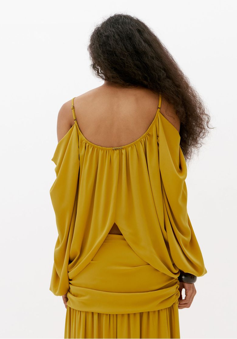 Vista-posterior-da-blusa-feminina-amarela-com-caimento-fluido-costas-abertas-e-mangas-longas-amplas