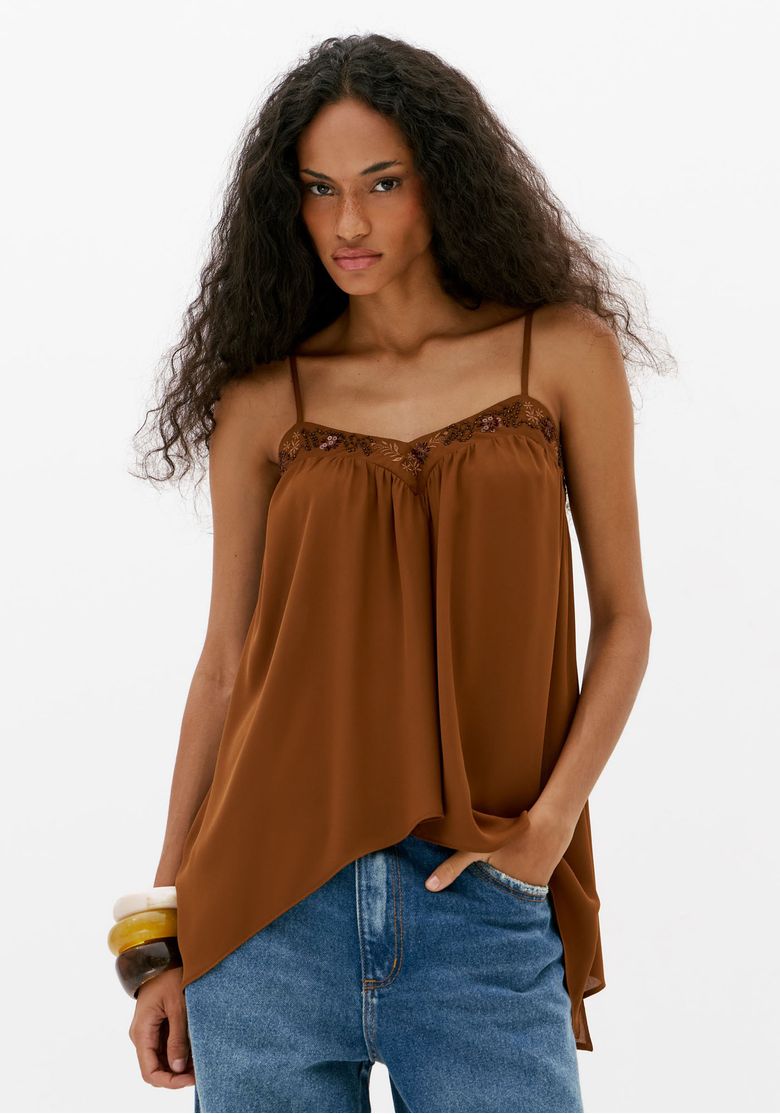 Blusa alongada feminina marrom com alças finas, decote em V bordado e barra assimétrica, combinada com calça jeans azul