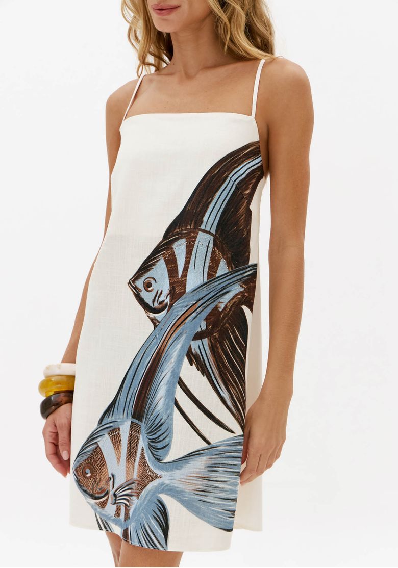 Vestido curto branco com estampa localizada de peixes azuis e marrons, detalhe frontal do caimento solto e modelagem trapézio