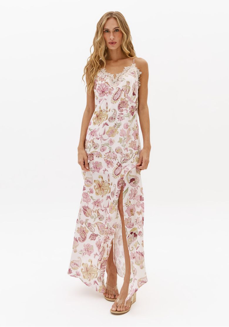 Modelo usando vestido super midi estampado branco com alças finas, renda no decote e fenda frontal, ideal para look casual feminino de verão