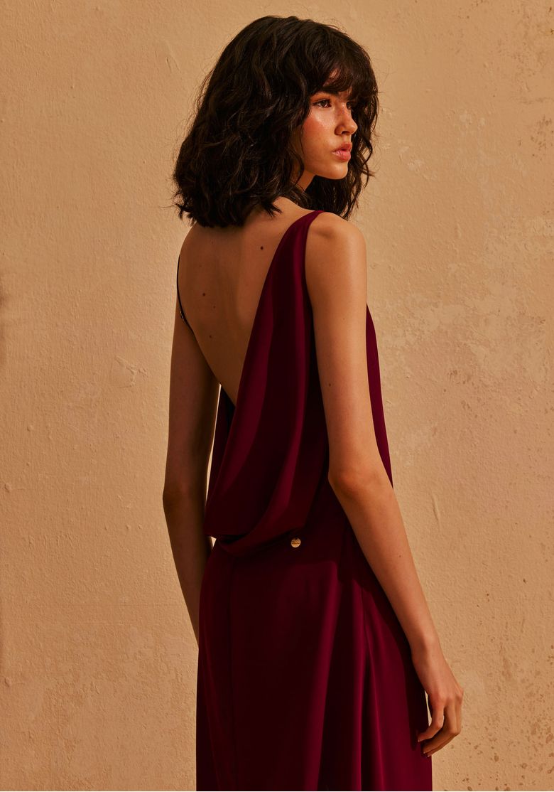 Costas do vestido longo bordô com degagê profundo e detalhe metálico nas costas, visual sofisticado feminino
