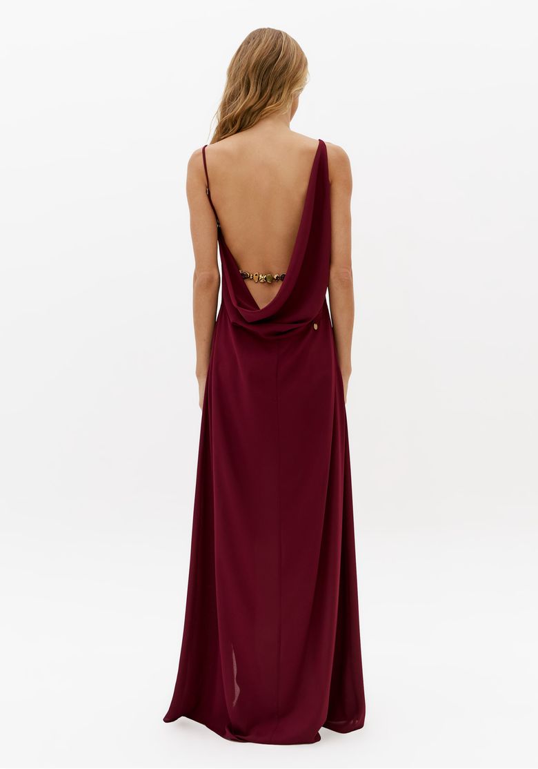 Vista traseira do vestido longo bordô com costas abertas, caimento fluido e detalhe de metal nas costas