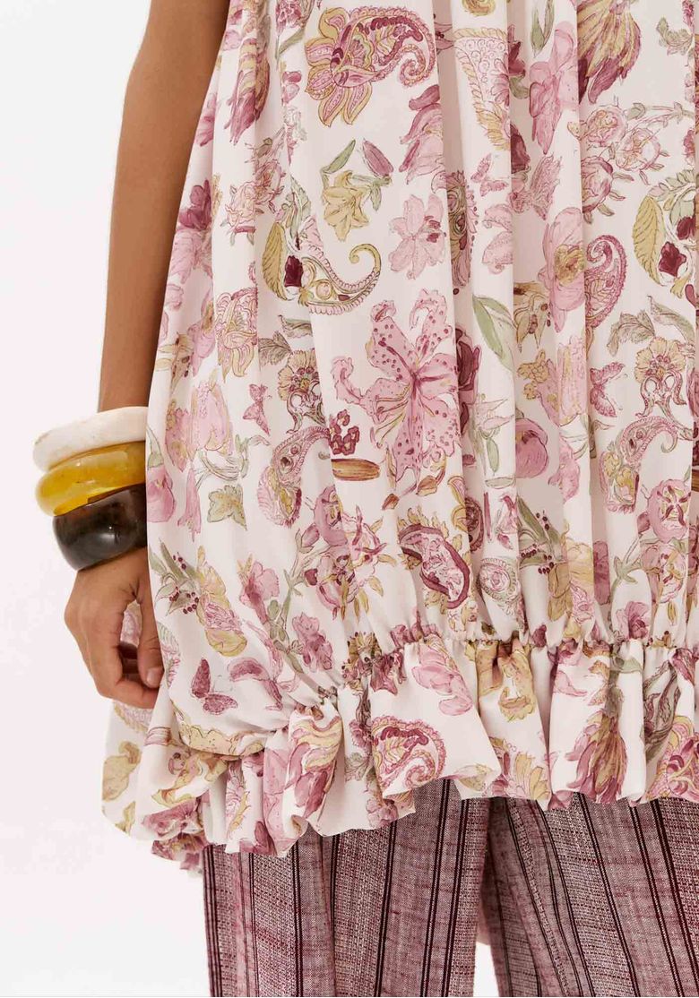 Close da barra franzida do vestido curto balonê estampado branco com motivos ornamentais em rosa
