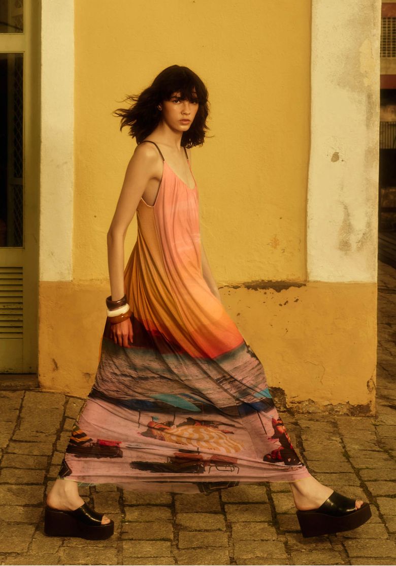 Modelo usando vestido longo de tule estampado amarelo com movimento fluido e visual casual de verão em ambiente externo
