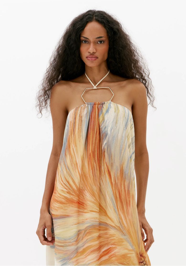 Close frontal de vestido longo estampado feminino com decote frente única, detalhe metálico e estampa em tons de laranja e azul