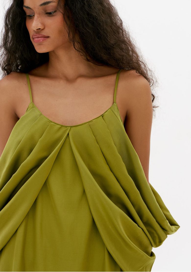 Detalhe do busto de vestido verde com alça fina, decote arredondado e sobreposição ampla