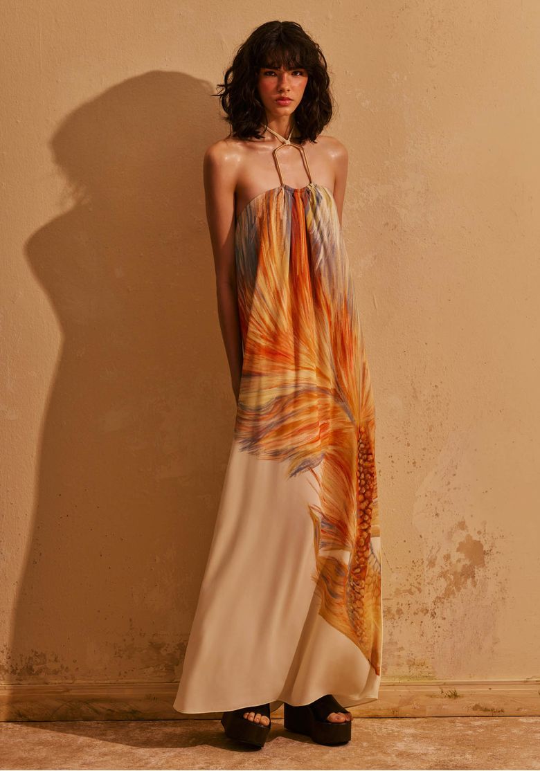 Modelo usando vestido longo estampado com detalhe de metal em editorial de moda com proposta sofisticada de verão