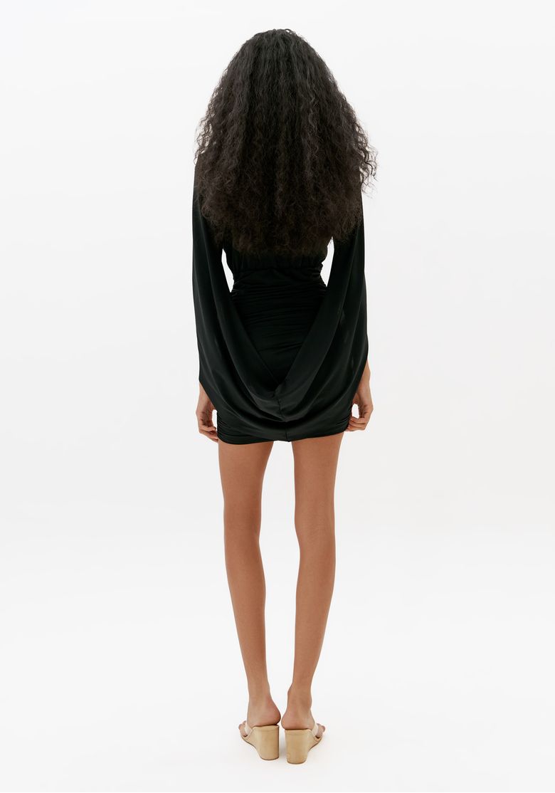 Vista costas de vestido curto preto ajustado com mangas capa longas e caimento justo