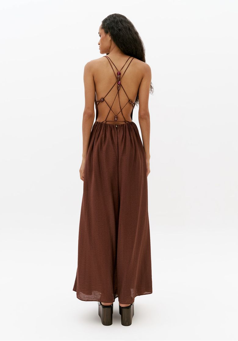 Vista traseira de vestido longo marrom com costas abertas, tiras cruzadas e aviamentos decorativos