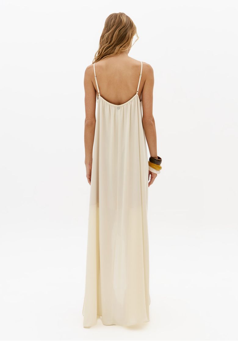 Vestido super midi off white visto de costas com alças finas reguláveis e modelagem longa fluida