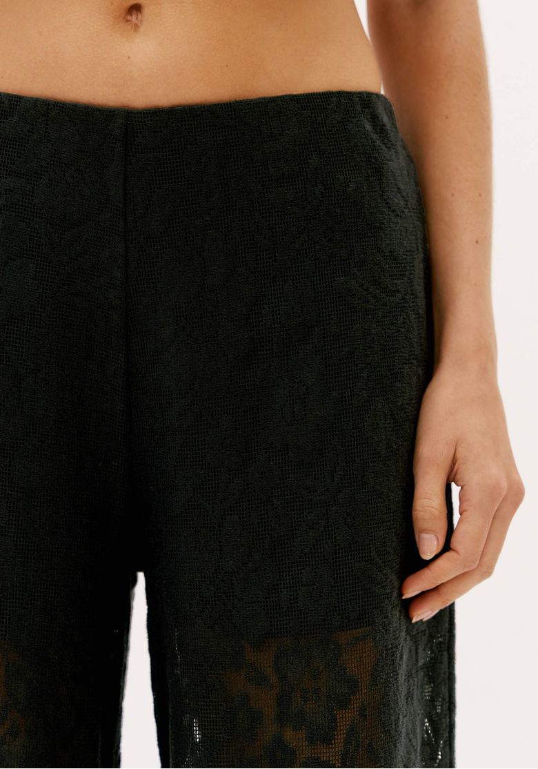 Close da cintura média e textura da renda preta da calça feminina full length