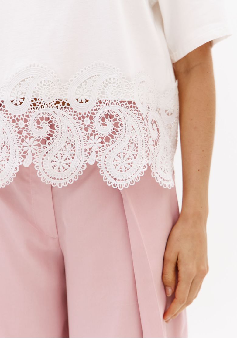 Close-da-barra-rendada-da-t-shirt-off-white-de-malha-leve-com-detalhe-vazado-ornamental-e-acabamento-delicado