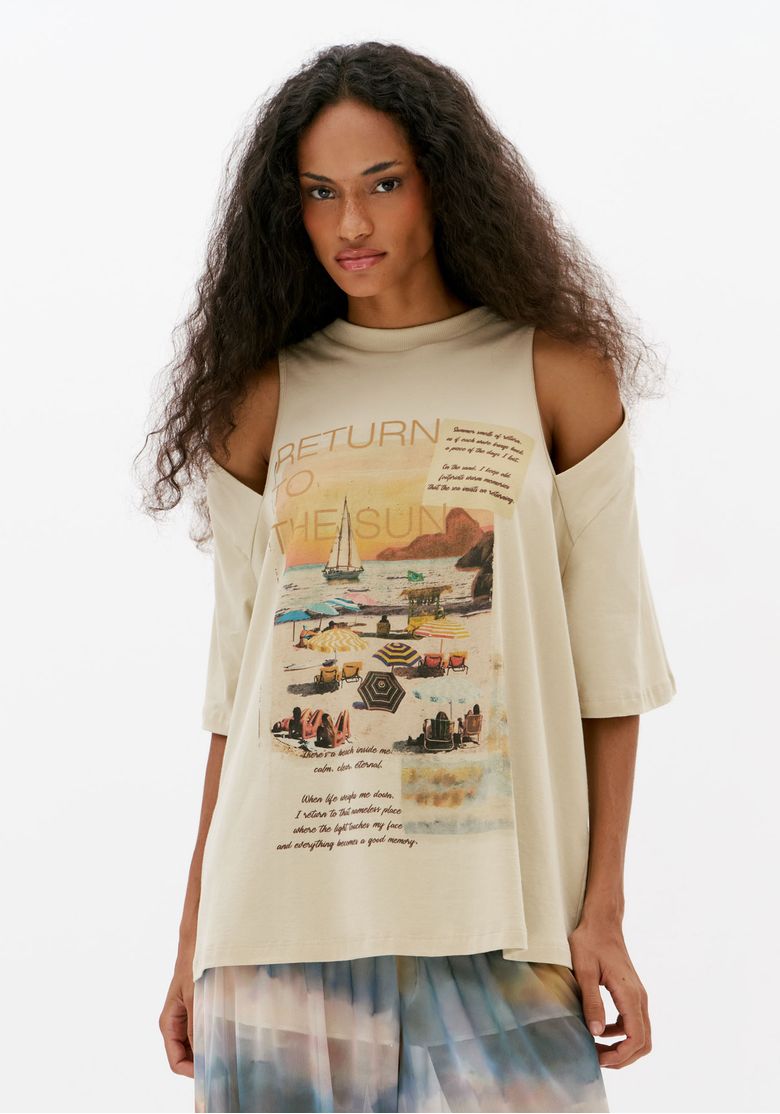 Vista frontal de camiseta feminina oversized off white com ombros vazados, gola redonda e estampa tropical