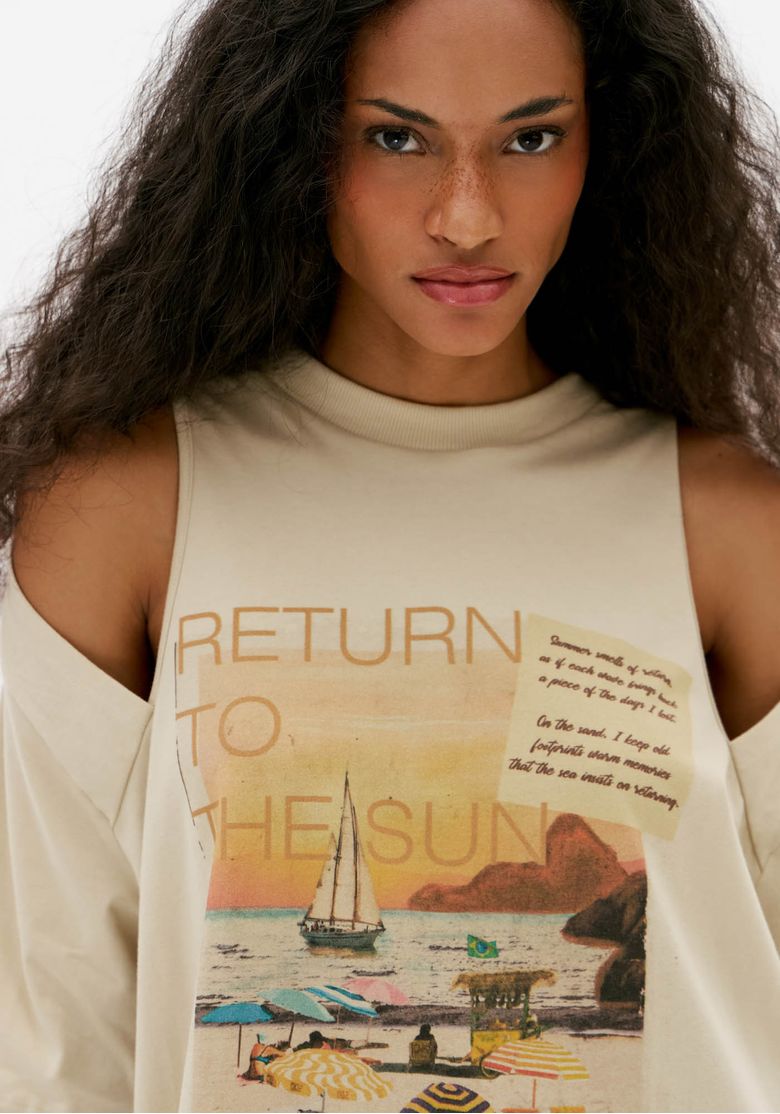 Close da estampa frontal da t-shirt oversized off white com lettering e ilustração de paisagem praiana