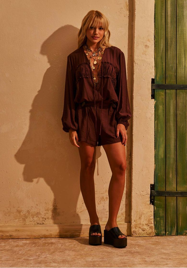 Modelo usando short curto marrom feminino de cintura média com blusa marrom de mangas longas e sandália plataforma em look casual sofisticado