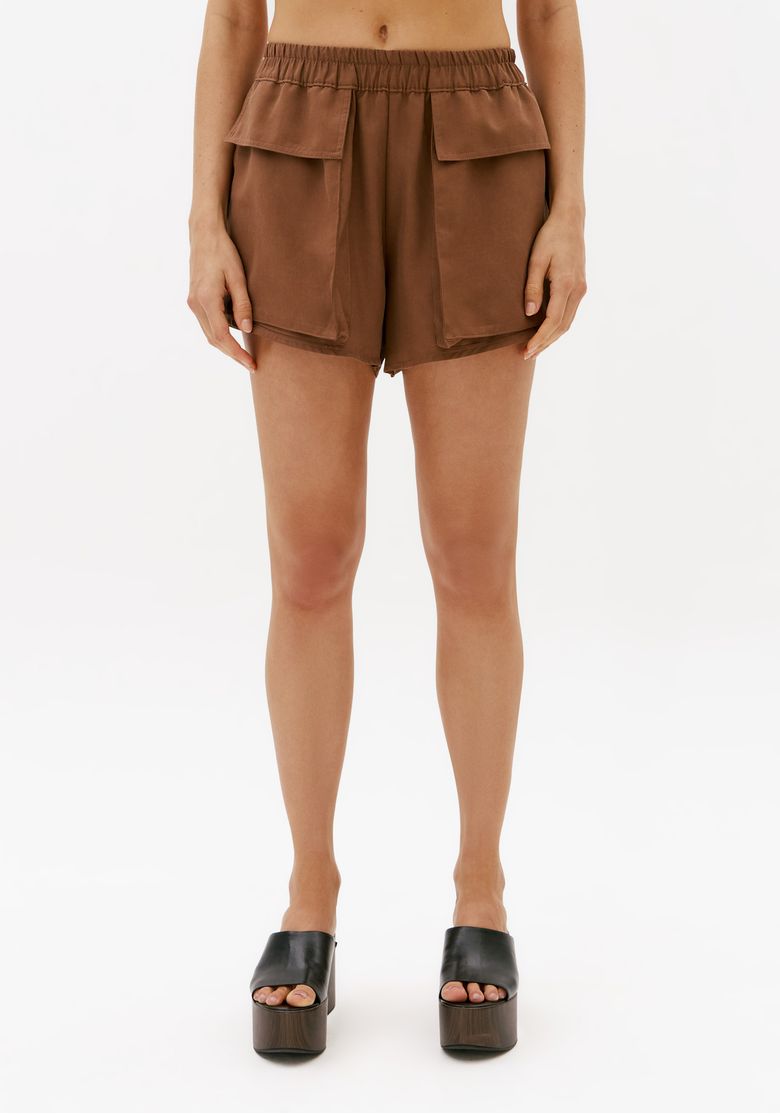 Vista frontal do short curto utilitário marrom feminino com cós elástico, modelagem solta e bolsos utilitários frontais