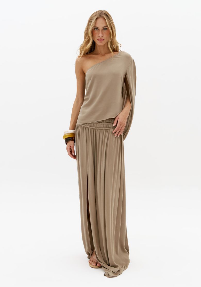 Modelo usando saia longa bege com franzidos e fenda frontal combinada com blusa de um ombro só em look elegante feminino