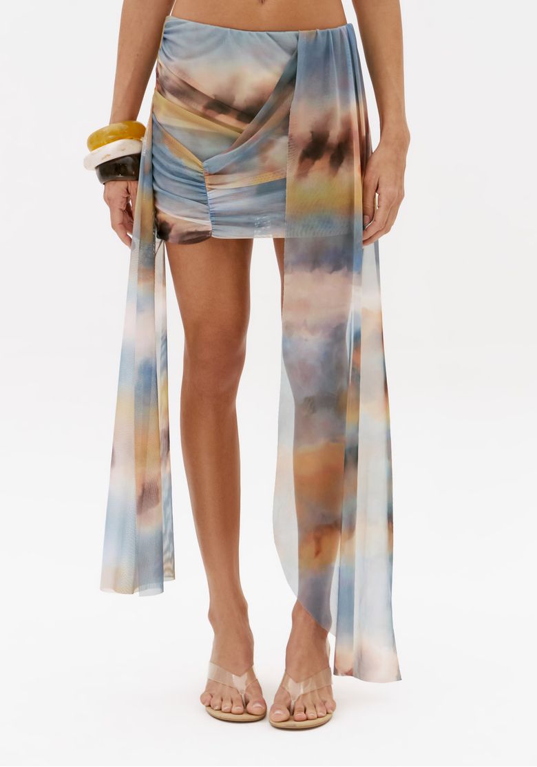 Close frontal da saia curta feminina de tule estampada azul com drapeado lateral e painel longo fluido estilo pareô