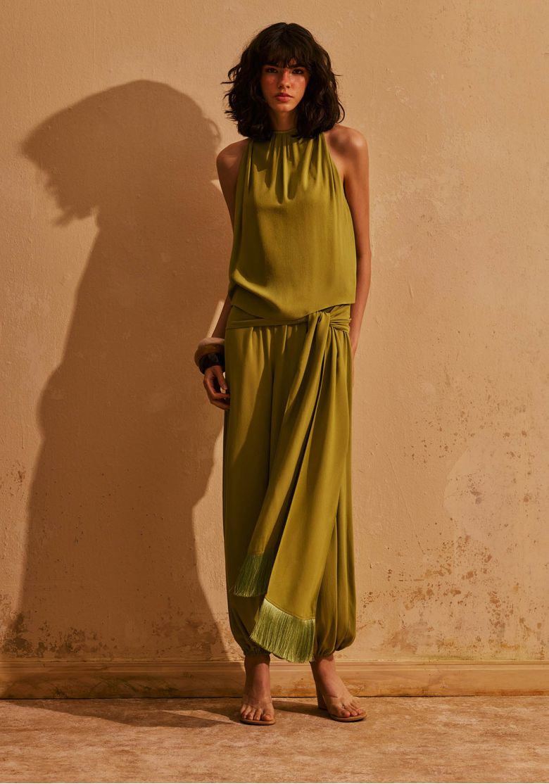 Modelo usando macacão longo aladim verde com faixa na cintura e franjas na barra, look feminino elegante para sunset
