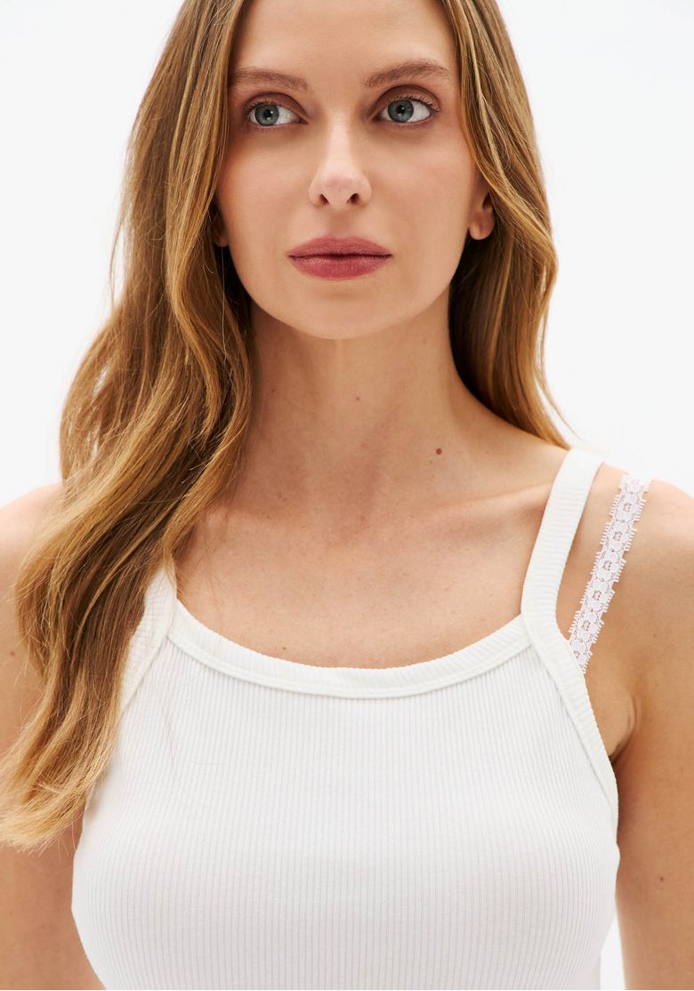 Close da regata canelada off white com textura canelada e detalhe de alça fina em renda