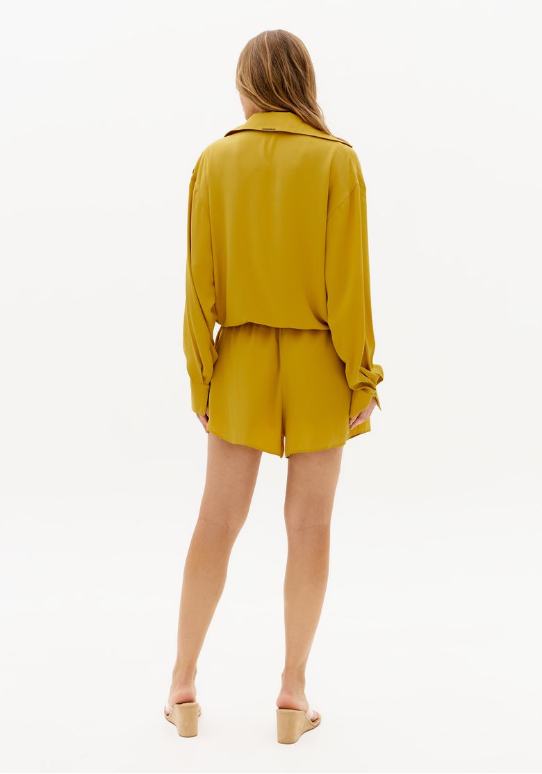 Vista-traseira-do-macacao-curto-amarelo-feminino-com-manga-longa-modelagem-solta-e-comprimento-curto