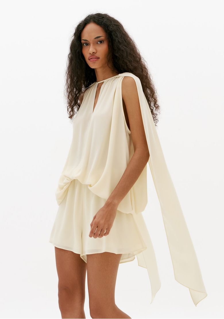 Macacão curto off white feminino em vista lateral com sobreposição fluida e efeito de capa sofisticado