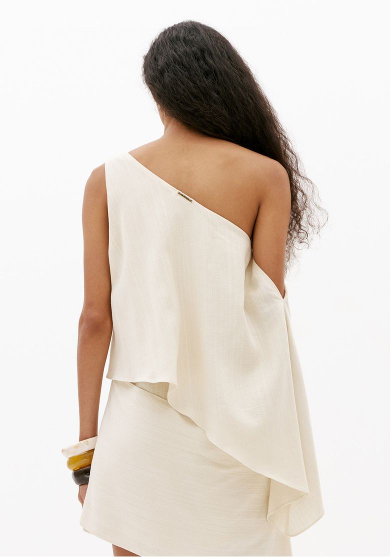 Detalhe costas do macacão assimétrico off white feminino com recorte de um ombro e acabamento minimalista