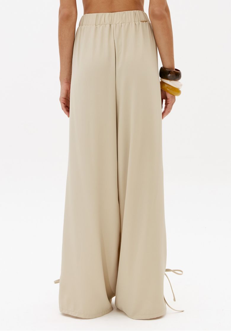 Vista traseira da calça barrel off white feminina com cós de elástico nas costas, modelagem ampla e comprimento longo