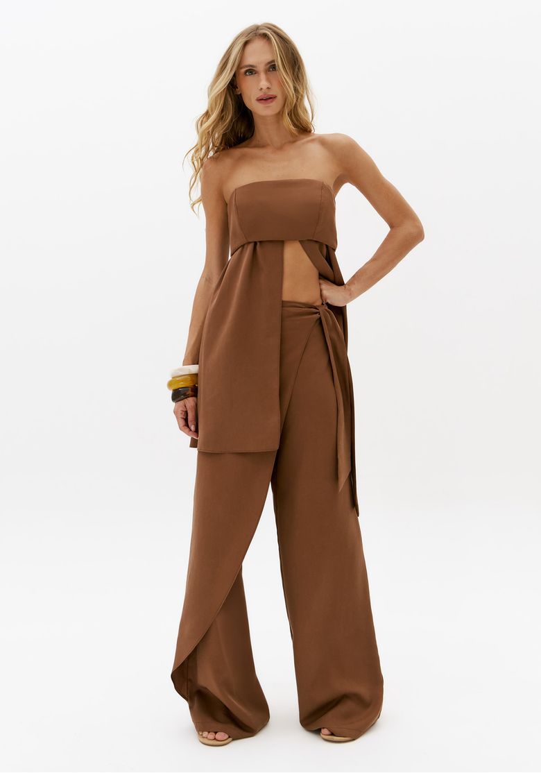 Modelo usando calça reta marrom cintura média com sobreposição frontal e amarração lateral em look monocromático feminino