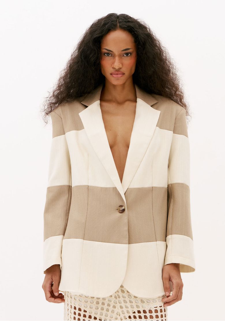 Blazer oversized bicolor feminino bege e off white visto de frente, com recortes em blocos de cor, lapelas amplas e manga longa